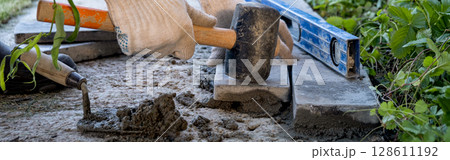 banner. Laying paving stones on cement mortar. Laying a garden path made of tiles. Self-laying of concrete paving slabs in the courtyard of the house. do it yourself. DIY 128611192