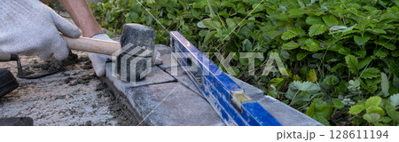 Laying paving stones on cement mortar. Laying a garden path made of tiles. Self-laying of concrete paving slabs in the courtyard of the house. do it yourself. DIY 128611194