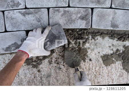 Laying paving stones on cement mortar. Laying a garden path made of tiles. Self-laying of concrete paving slabs in the courtyard of the house. do it yourself. DIY 128611205