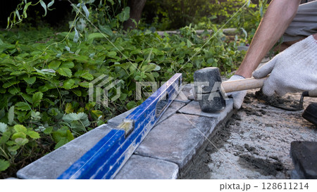 Laying paving stones on cement mortar. Laying a garden path made of tiles. Self-laying of concrete paving slabs in the courtyard of the house. do it yourself. DIY Laying paving stones on cement mortar. Laying a garden path made of tiles. Self-laying of concrete paving slabs in the courtyard of the house. do it yourself. DIY 128611214