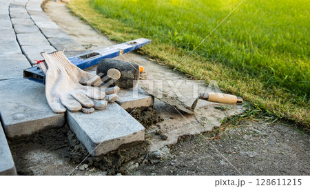 Laying paving stones on cement mortar. Laying a garden path made of tiles. Self-laying of concrete paving slabs in the courtyard of the house. do it yourself. DIY Laying paving stones on cement mortar. Laying a garden path made of tiles. Self-laying of concrete paving slabs in the courtyard of the house. do it yourself. DIY 128611215