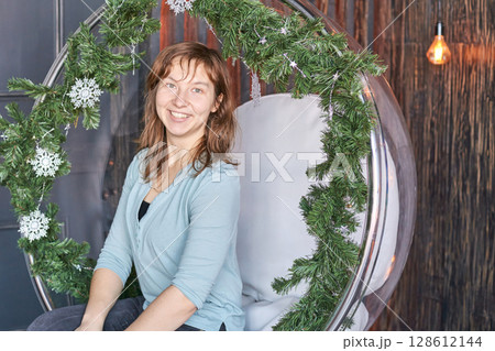 Smiling caucasian female adult in holiday decorated chair 128612144