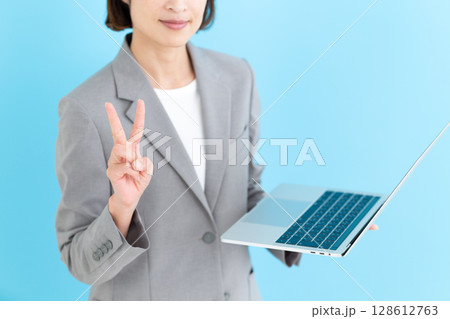 ノートパソコンを持ってピースをするミドル女性ビジネスウーマン ノートパソコンを持ってピースをするミドル女性ビジネスウーマン 128612763