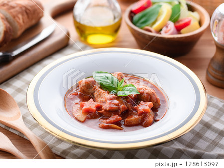 鶏手羽元のトマト煮込みとパンの洋食テーブルイメージ 鶏手羽元のトマト煮込みとパンの洋食テーブルイメージ 128613097