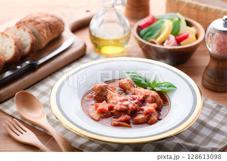 鶏手羽元のトマト煮込みとパンの洋食テーブルイメージ 128613098