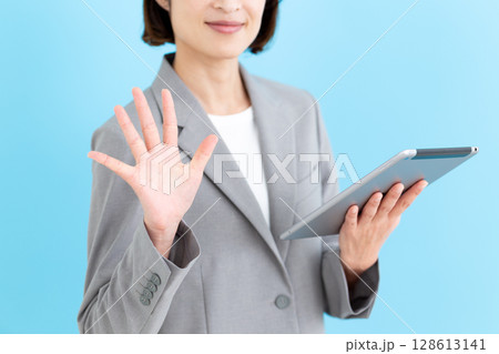 タブレットを持って5本指を立てるミドル女性ビジネスウーマン 128613141