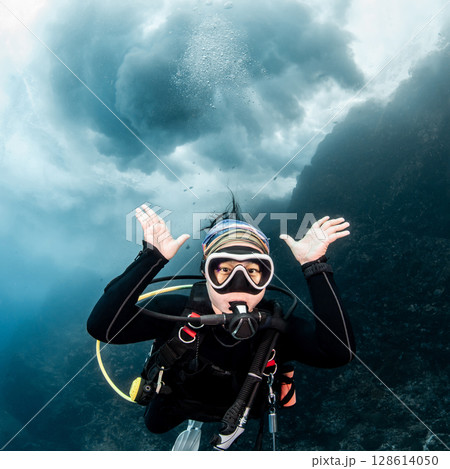 Asian female scuba diver looking at camera posing with the stunning wave breaking exploding above 128614050