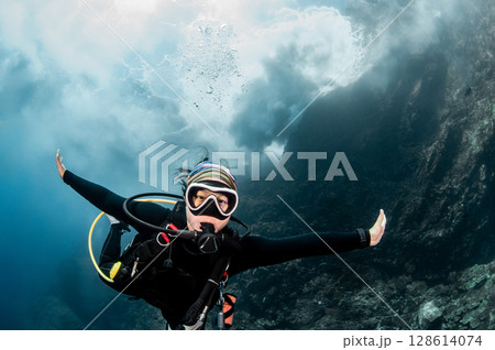 Asian female scuba diver looking at camera posing with the stunning wave breaking exploding above 128614074