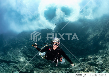 Asian female scuba diver looking at camera posing with the stunning wave breaking exploding above 128614083