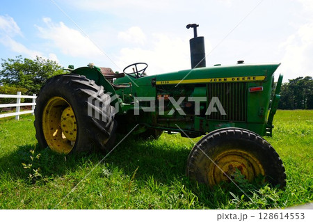 牧場の古い壊れたトラクターと白いフェンス 128614553