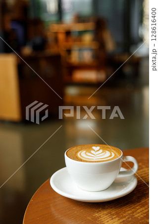 Cup of hot milk latte coffee on table by the window. Cup of hot milk latte coffee on table by the window. 128616400