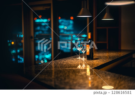 夜景の見えるバーカウンターに置かれたワインとグラス 夜景の見えるバーカウンターに置かれたワインとグラス 128616581
