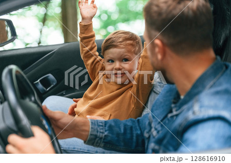 Father with his little son are sitting in the car Father with his little son are sitting in the car 128616910