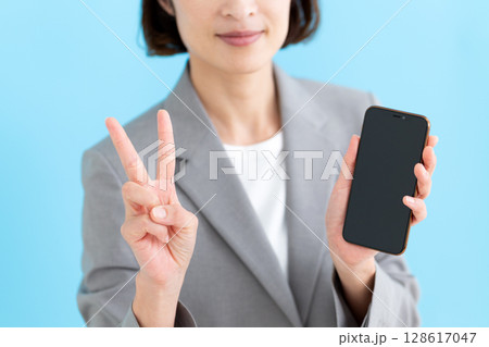 スマホを持って2本指を立てるミドル女性ビジネスウーマン 128617047