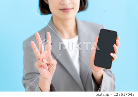 スマホを持って3本指を立てるミドル女性ビジネスウーマン 128617048