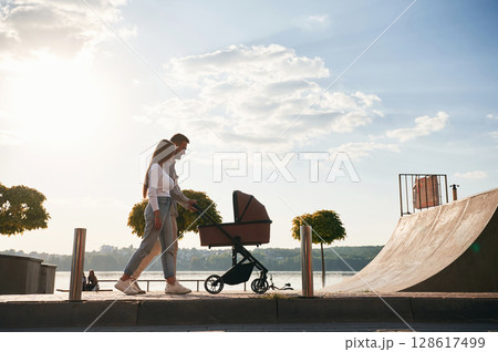 Side view. A young couple with a baby pram is walking together 128617499