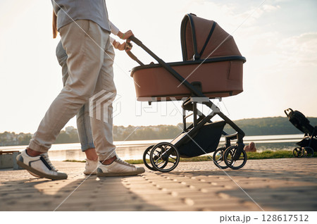 View from below of legs. A young couple with a baby pram is walking together 128617512