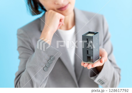 オフィスビルの模型を持って悩むミドル女性ビジネスウーマン 128617792