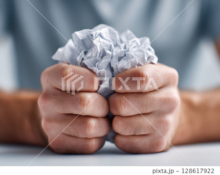 Person clenches crumpled paper ball in their hands showing frustration and stress during global financial crisis that can lead to bankrupt situations and economic challenges 128617922