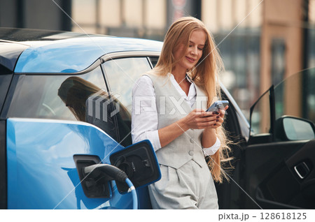 Process of charging, waiting. Woman on the electric cars station at daytime 128618125