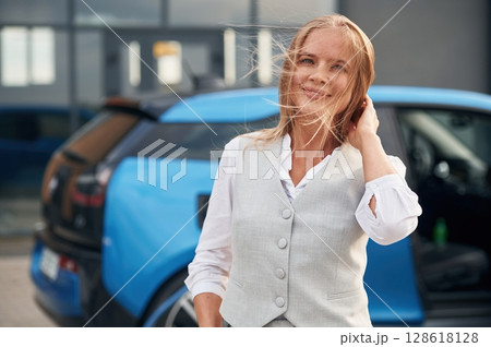 Woman on the electric cars charge station at daytime 128618128