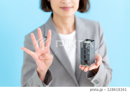 オフィスビルの模型を持って4本指を立てるミドル女性ビジネスウーマン 128618161