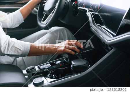 Close up view. Woman is sitting in a car and driving it Close up view. Woman is sitting in a car and driving it 128618202