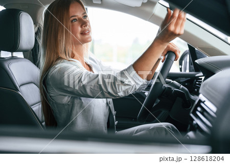 Side view. Woman is sitting in a car and driving it Side view. Woman is sitting in a car and driving it 128618204