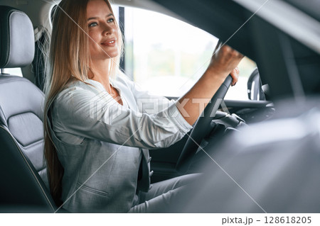 Side view. Woman is sitting in a car and driving it Side view. Woman is sitting in a car and driving it 128618205