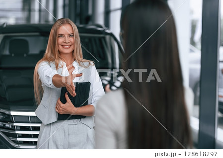 Female manager is helping woman customer in the car dealership salon Female manager is helping woman customer in the car dealership salon 128618297