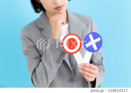 丸ばつの札を持って悩むミドル女性ビジネスウーマン 128618317