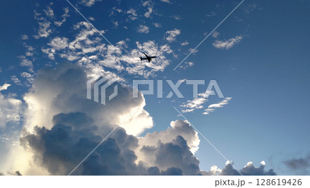 夕日に照らされる雲と飛行機 128619426