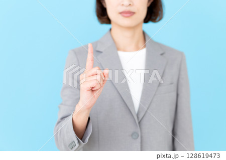 グレーのスーツを着て人差し指を立てるミドル女性ビジネスウーマン グレーのスーツを着て人差し指を立てるミドル女性ビジネスウーマン 128619473