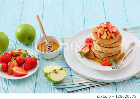 pancakes topped with apple slices and strawberries pancakes topped with apple slices and strawberries 128620579