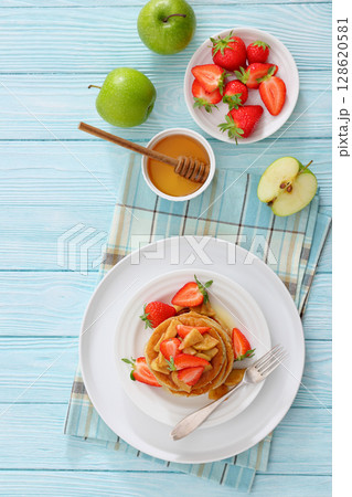 pancakes topped with apple slices and strawberries pancakes topped with apple slices and strawberries 128620581