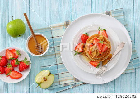 pancakes topped with apple slices and strawberries pancakes topped with apple slices and strawberries 128620582