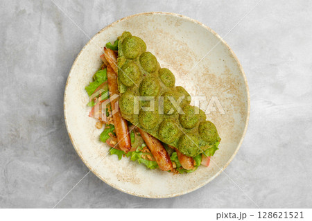Unique green waffle sandwich with grilled sausage and fresh vegetables on a plate 128621521