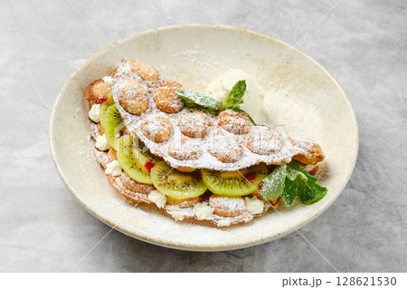 Delicious dessert featuring fresh kiwi, whipped cream, and dusted sugar presented in a modern bowl 128621530
