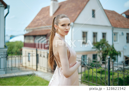 Model poses in elegant dress near historic building on sunny day 128621542