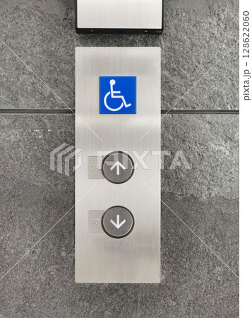 Up/down elevator buttons and wheelchair symbols on the cement wall. Up/down elevator buttons and wheelchair symbols on the cement wall. 128622060