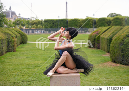 Ballet dancer in graceful seated pose on pedestal in green park Ballet dancer in graceful seated pose on pedestal in green park 128622164