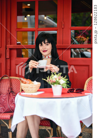 Elegant woman having coffee at red Parisian cafe 128622183