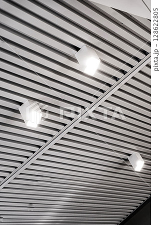 Ceiling with bright lights in a modern warehouse, shopping center building, office or commercial real estate object. Directional LED lights on rails under the ceiling 128622805
