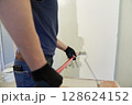 With a roller, apply paint to the surface, paint the walls in the apartment, does repairs with white paint. With the ability to copy. High quality photo 128624152