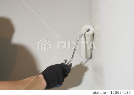 Roller painting of the wall, working painting on the surface, painting the walls in the apartment, repair with white paint. With space to copy. High quality photo 128624156