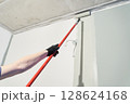 With a roller, apply paint to the surface, paint the walls in the apartment, does repairs with white paint. With the ability to copy. High quality photo 128624168
