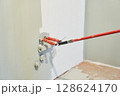 Insulated wires are sticking out of the wall. Close-up of a roller painting a wall in the color of hakka. Apartment painting, renovation. There is a place to copy. High quality photo 128624170