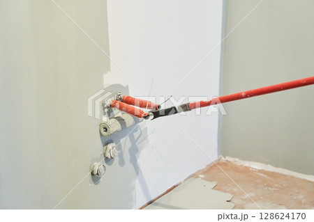 Insulated wires are sticking out of the wall. Close-up of a roller painting a wall in the color of hakka. Apartment painting, renovation. There is a place to copy. High quality photo 128624170