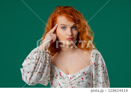 Ginger woman tapping temple thoughtful expression suggesting critical thinking 128624419