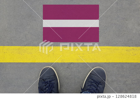Start on an asphalt road with the Latvian flag and legs in shoes. Business, Immigration and Travel  128624818